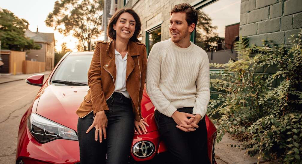 Couple-Standing-in-Front-of-Toyota-Corolla-in-Red
